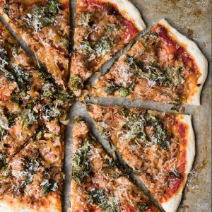 caramelized onion, kale and sausage pizza sliced on a baking sheet
