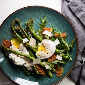 blue plate with roasted asparagus, poached eggs, crispy prosciutto, and shaved parmesan