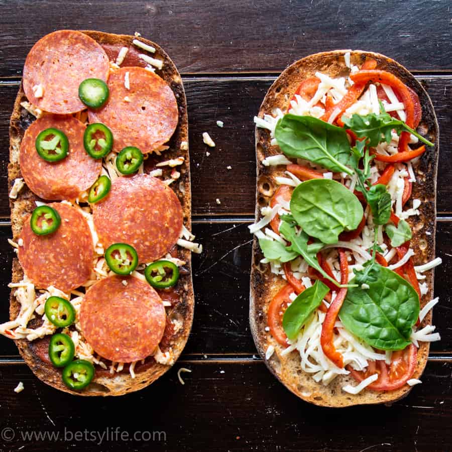 two french bread pizzas covered in toppings ready to be baked 