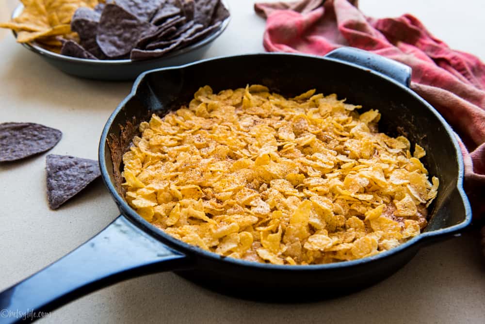 cast iron skillet filled with corn dip topped with corn flakes