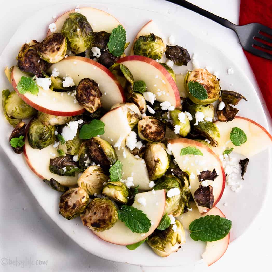 Roasted Brussels sprout salad with apples, feta and mint on an oval white dish 