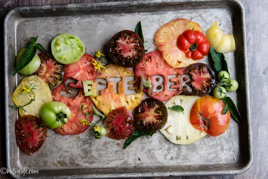 sliced heirloom tomatoes on a metal tray that spell out September 
