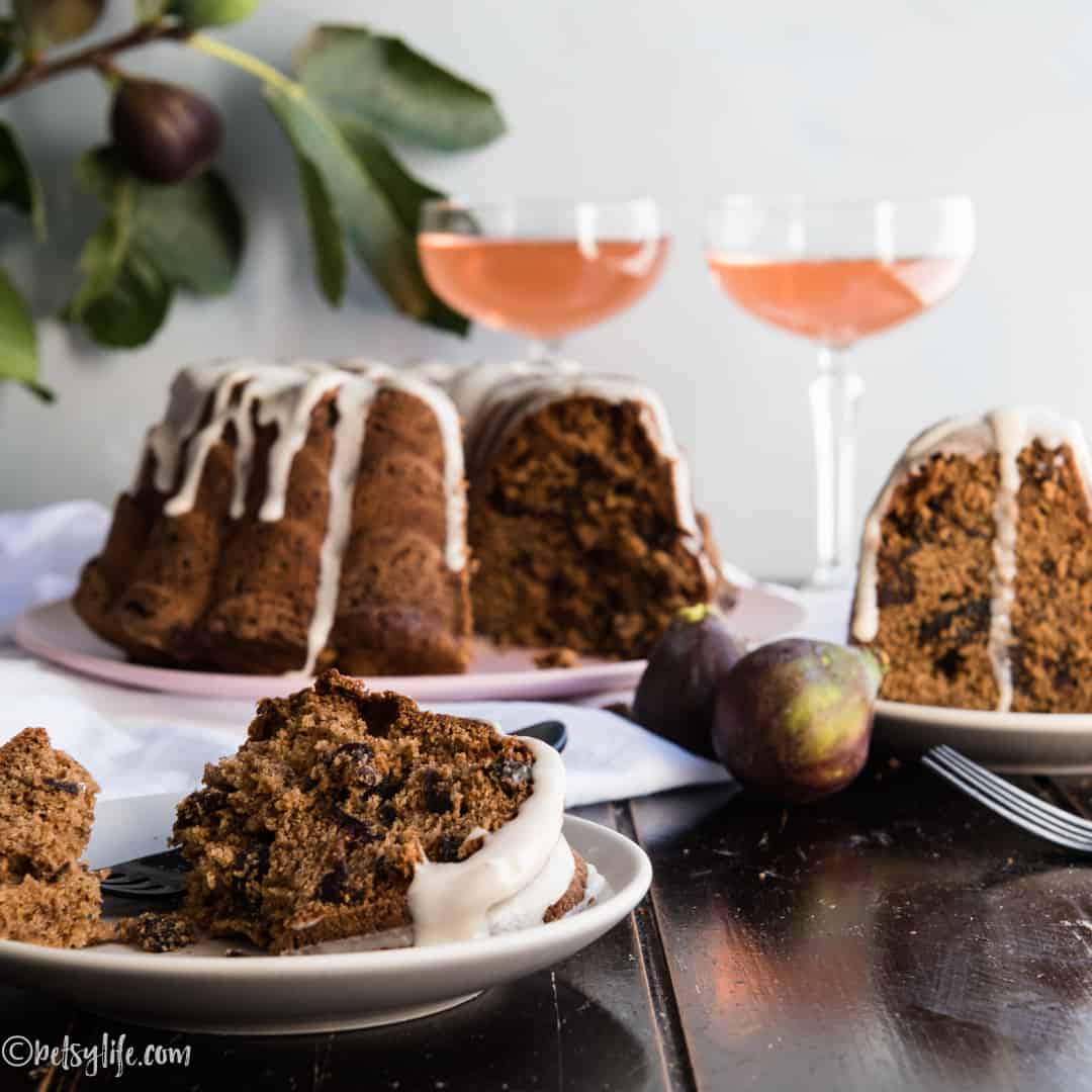 bourbon fig bundt cake with two slices on plates and two glasses of pink rosé wine