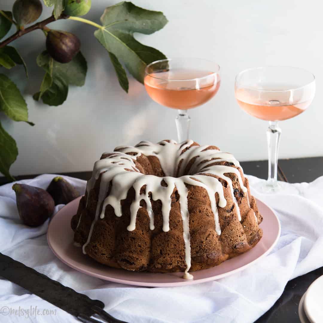 bourbon fig bundt cake on a pink plate in front of two glasses of rosè wine