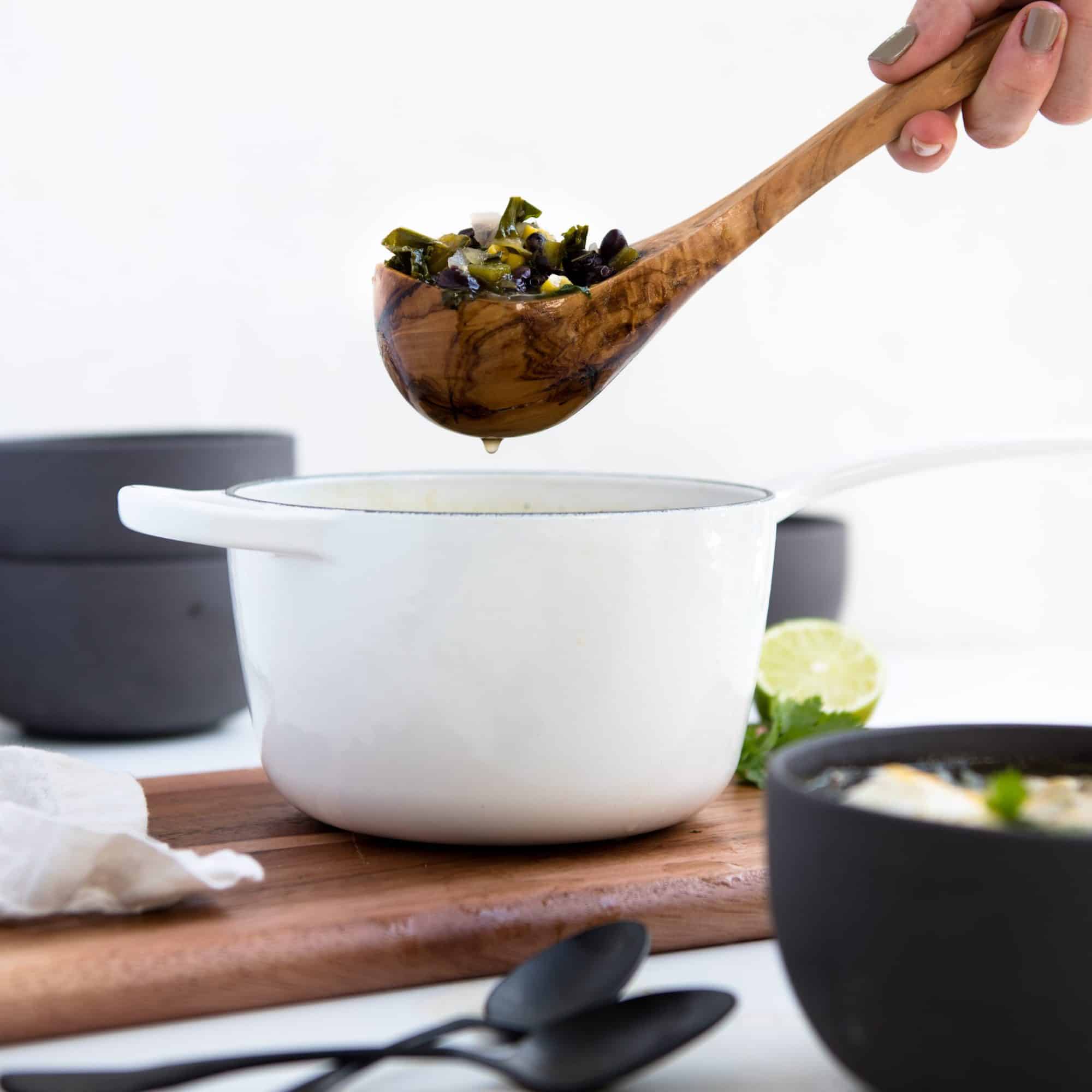 wooden ladle spooning soup from a white pot 