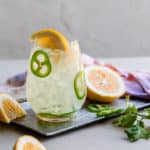 Coconut water and lemonade cocktail with sliced jalapenos and lemon wedges
